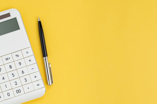 Flat lay or top view of black pen with white calculator on vivid yellow background table with blank copy space, cost and expense, budget, tax, math or investment calculation