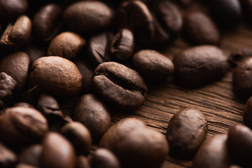 close up view of fresh roasted coffee beans scattered on wooden table