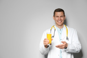 Nutritionist with glass of juice on light grey background. Space for text
