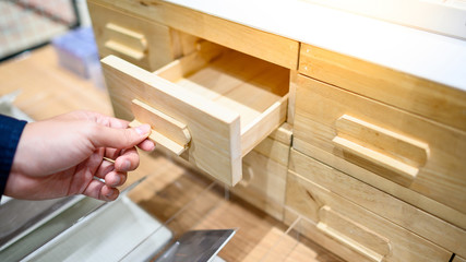 Male hand pulling and opening drawer on wooden cabinet. Home furniture and decoration shopping...