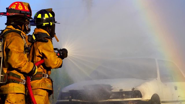 Firefighter on duty in Burning car. Three firefighters fighting a fire with a hose and water during a firefighting. Firefighters during battle and explosion of fire emergency case for danger mission.