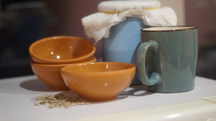 a blue earthenware jug and mug, small brown saucers with grits on a dark background