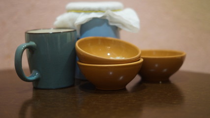 a blue earthenware jug and mug, small brown saucers with grits on a dark background