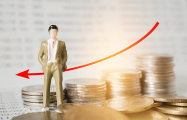 miniature business man and graph with blurred coins and bankbook , business and finance concept