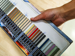 Man's male hand holding a color palette sample of different colors for customers to chose from while renovating or redesigning home interior