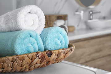 Wicker tray with clean soft towels in bathroom, closeup
