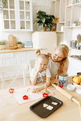 mom and daughter cook cookies together in the kitchen.