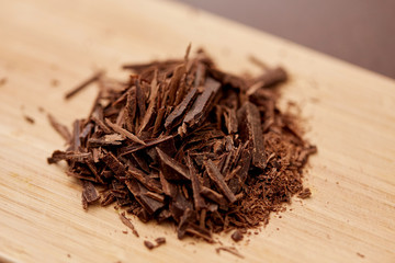 sweets, confectionery and culinary concept - chocolate chips on wooden board on brown background