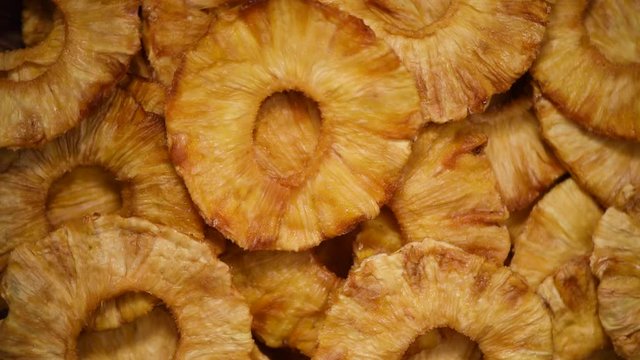 Slices of dried pineapple on rotating background. Top view. Vegan, vegetarian diet. Healthy lifestyle. Dried fruits background. Sweet pineapples, organic food.