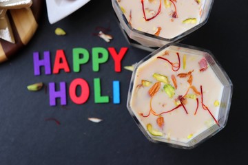 Indian Holi festival food or drink Thandai. It is an Indian cold drink prepared with a mixture of Milk, Dry fruits, sugar & spices. Garnished with Almonds, Pistachio & saffron. Happy Holi. copy space.