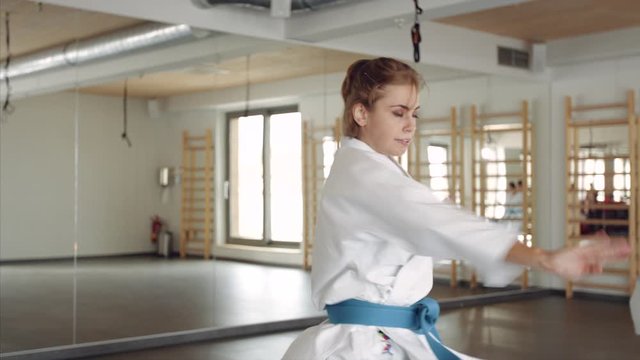 Group of young women practising karate indoors in gym.
