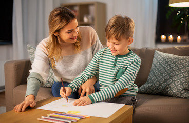 family, leisure and people concept - mother and little son with colored pencils and paper draw at home
