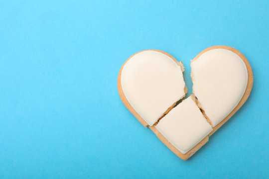 Broken heart shaped cookie on light blue background, top view with space for text. Relationship problems concept