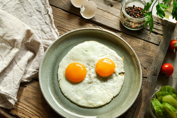 Tasty fried eggs for breakfast. Fried eggs in a plate on a wooden table background, top view.
