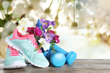 Composition with spring flowers and sports items on wooden table against blurred background