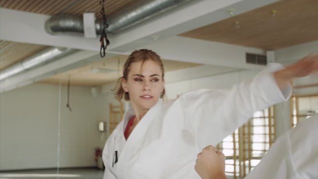 Young women practising karate indoors in gym.