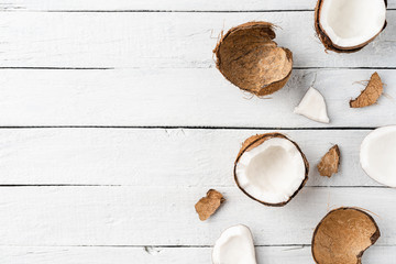 Broken coconut on white wooden background with copyspace. Top view