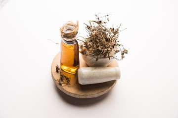Fototapeta premium Ayurvedic Maha Bhringraj or Mahabhringraj Hair Oil with dried leaves and mortar, selective focus