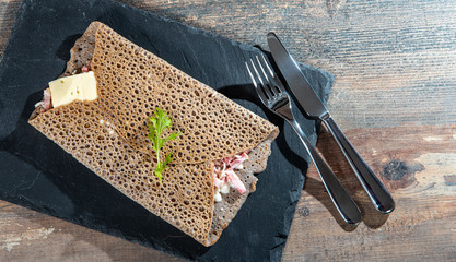 Breton crepe with cheese and bacon on the wooden background