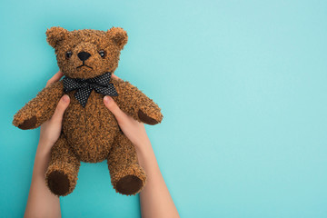 Cropped view of woman holding teddy bear on blue background