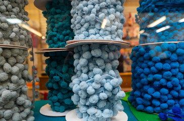 Reels of blue pom pom bobble trim displayed in a shop window