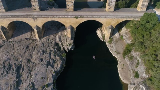 Aerial shot of Canoe Kayak, alone on the Gardon River under the Pont du Gard. A aqueduct built by romans close to Nimes, South of France, classified UNESCO.