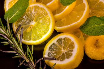 Lemon slices, mint leaves, rosemary sprig, on a black background,close-up