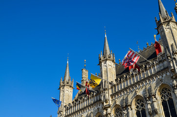 Fototapeta premium Bruges, Flanders, Belgium. August 2019. Burg square is one of the most important. The splendid town hall overlooks it. Detail of the spiers and flags that decorate the facade.