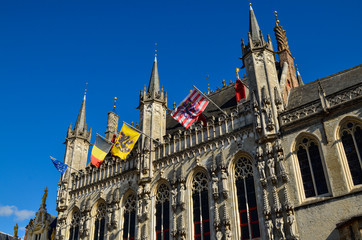 Fototapeta premium Bruges, Flanders, Belgium. August 2019. Burg square is one of the most important. The splendid town hall overlooks it. Detail of the spiers and flags that decorate the facade.