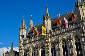 Fototapeta na wymiar Bruges, Flanders, Belgium. August 2019. Burg square is one of the most important. The splendid town hall overlooks it. Detail of the spiers and flags that decorate the facade.