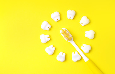 Toothbrush with teeth models making sun on a yellow background. Copy space.