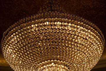 Chandelier in temple. Luxury shiny texture of circle rows of diamond shaped glass gems closeup. Glamour shiny backdrop with copy space. Close-up of gorgeous chandelier with crystal pendants.