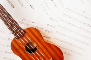 Naklejka premium High-quality beautiful Wallpaper musical wooden instrument Ukulele with white nylon strings on the background of musical notes. Top view, Lifestyle , mood toning.