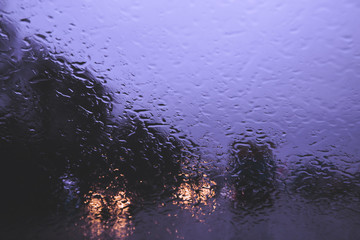 City road seen through rain drops on the car windshield.