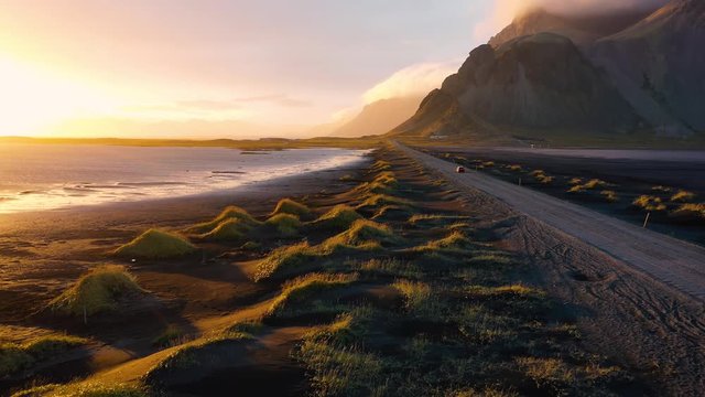 Flying over a dirt road at sunset with Vestrahorn mountain in Iceland