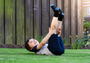 Active kid having fun lying down on grass in the garden. Healthy Child boy laying on lawn and...