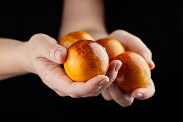 Blood oranges with red peel in hands on black background