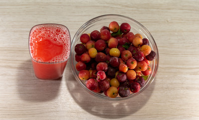 Fresh fruits and acerola juice on a wooden surface