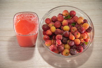 Fresh fruits and acerola juice on a wooden surface