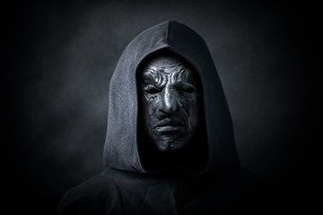 Scary figure in hooded cloak with mask