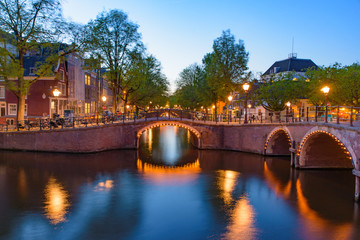 Reflection of bridge along the canal at night in Amsterdam, Netherlands