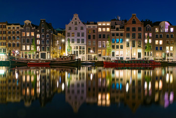 Fototapeta na wymiar Reflection of the buildings along the canal at night in Amsterdam, Netherlands