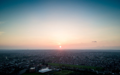 Suburban London sunset. A low setting sun resting over the horizon of a clear sky with rows of houses in the North London haze.