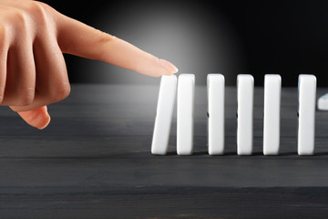 Woman hand toppling dominoes. Chain reaction business concept