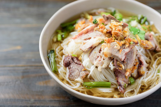 Rice noodles soup with beef in a bowl on wooden background, Asian food