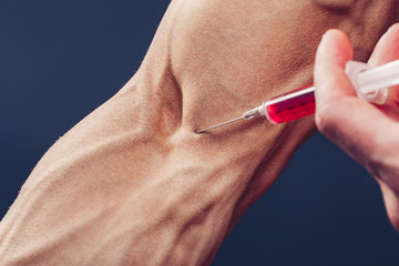 Hand of a muscular man with a syringe. Doing a shot of steroids