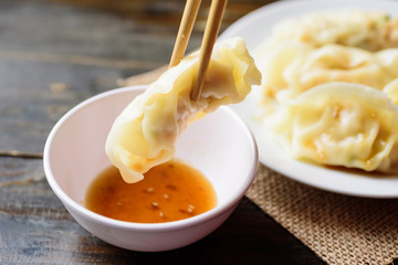 Steamed wonton dumpling stuffed with minced pork and shrimp eating with sesame oil  sauce by chopsticks, Asian food