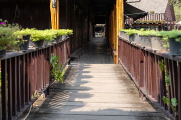 Fototapeta na wymiar Wooden bridge pathway with plant pots on top Travel into an ancient wooden house