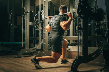 Fit man doing squats in a training machine