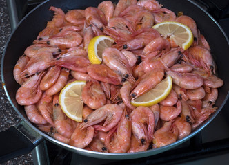Prawns in a frying pan cooking with fresh herbs and tomatoes.